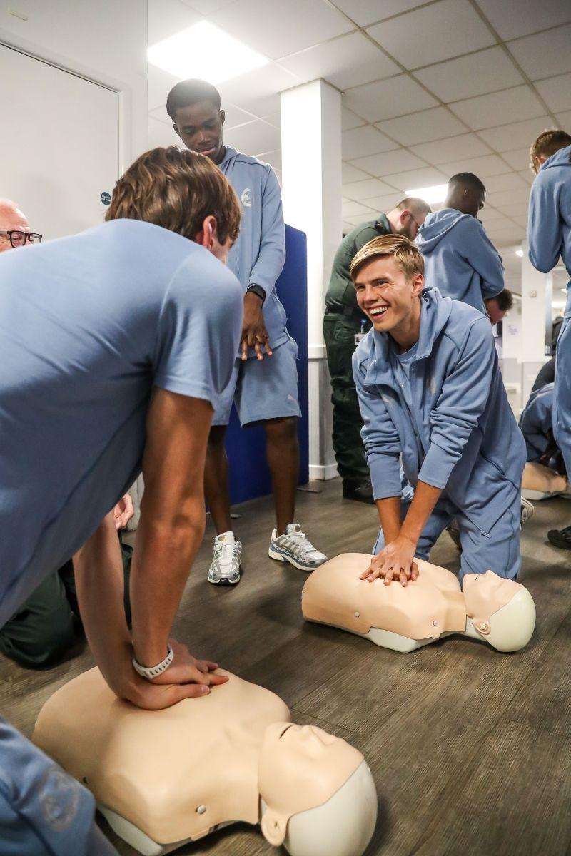 A group of men practising cpr on a dummy